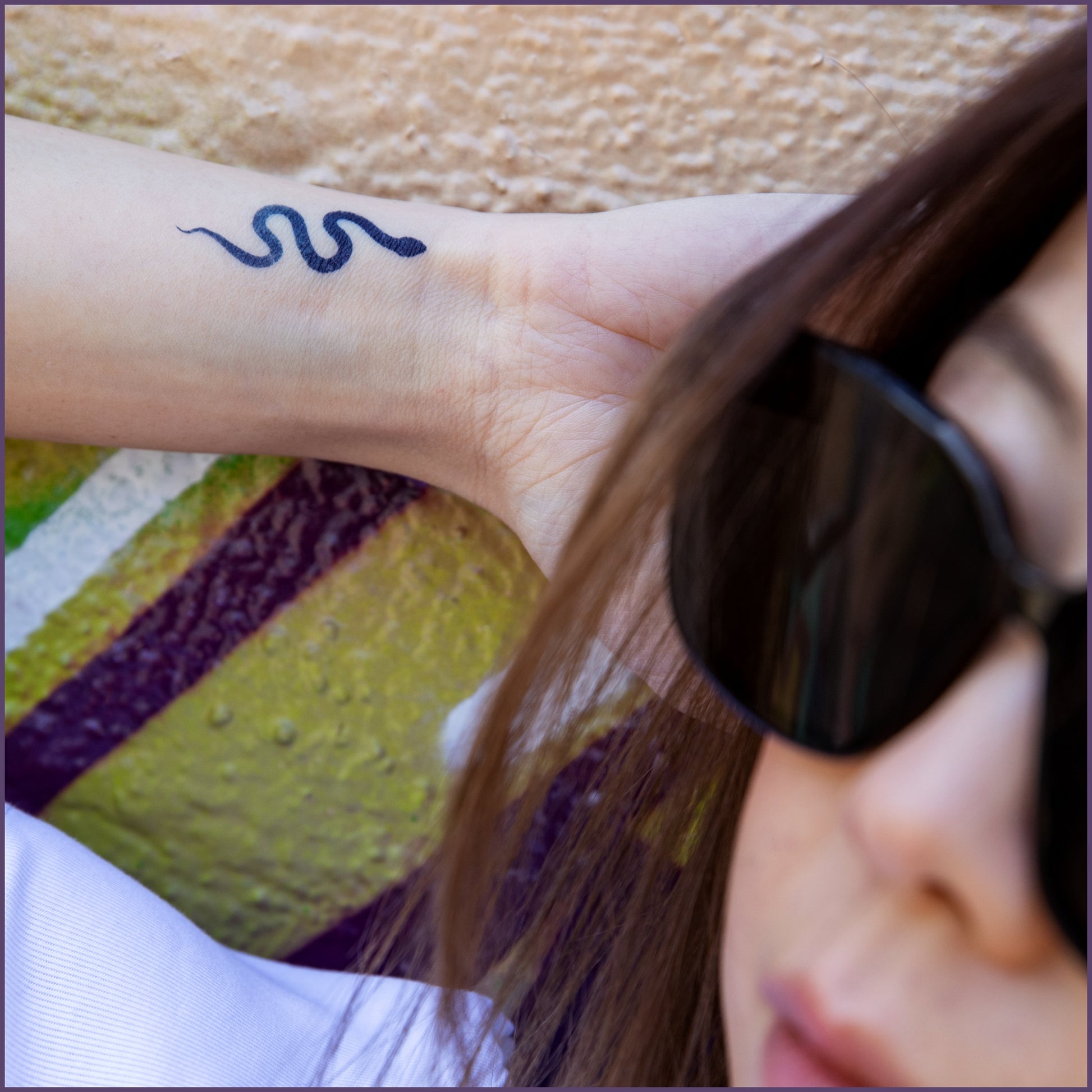 A small tattoo of a snake on a woman's inner wrist