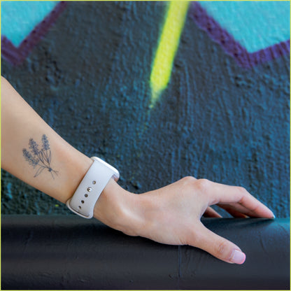 An arm is resting on a dark pipe in front of a blue and yellow graffiti wall. There is a tattoo of a bouquet of lavender on the inner forearm.